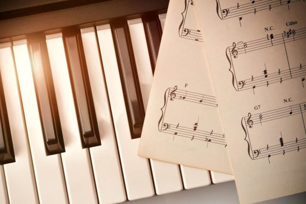 Piano keyboard in diagonal with golden shine and sheet music. Horizontal Composition.Top view